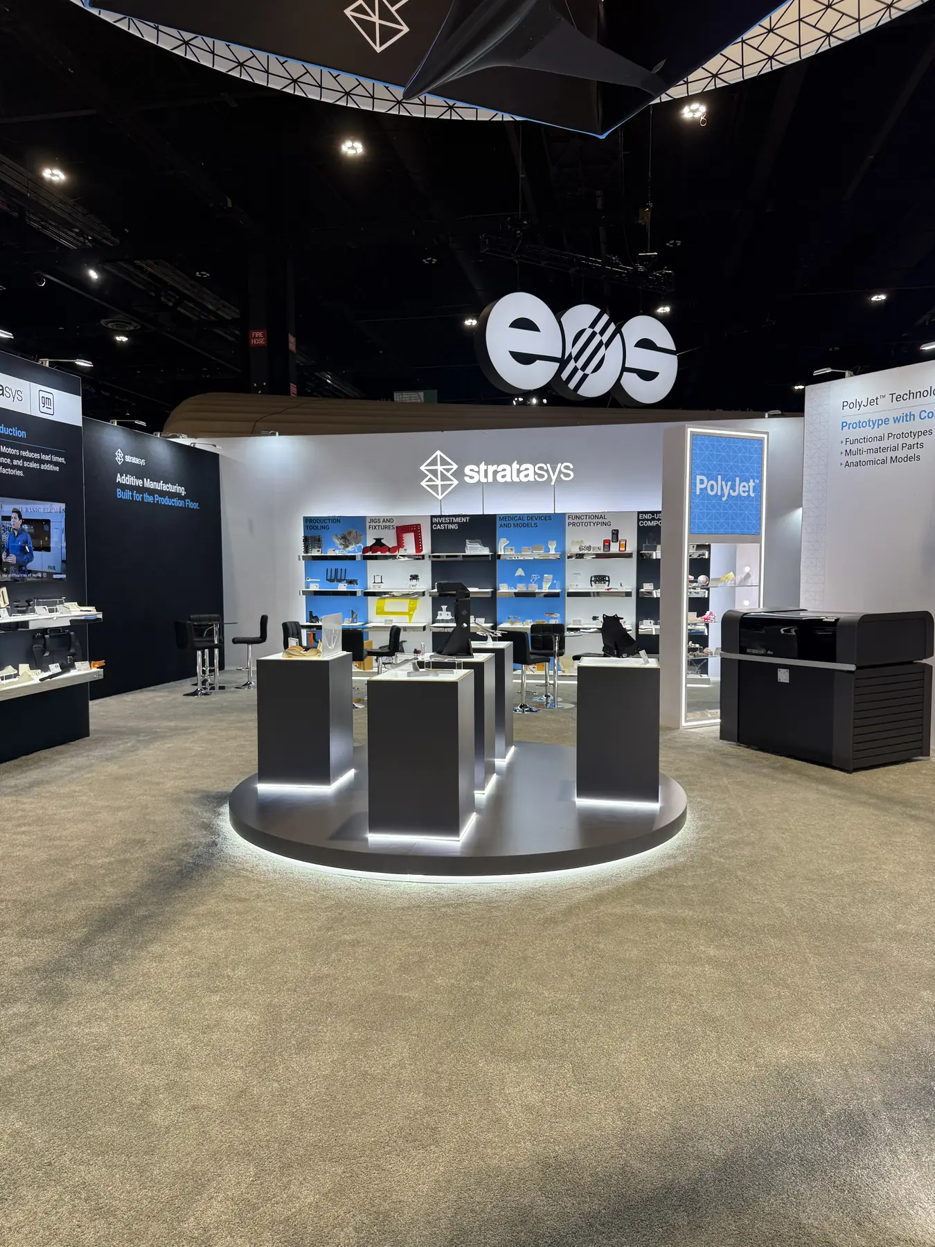 Stratasys exhibition stand at IMTS 2026 in Chicago, with a lit pedestal display and an application wall of printed parts